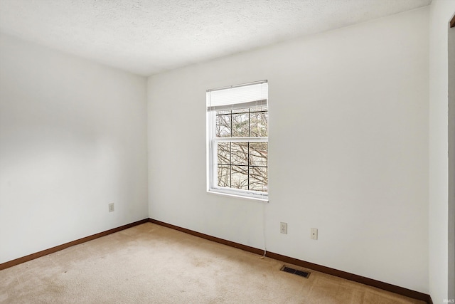 carpeted empty room featuring a textured ceiling