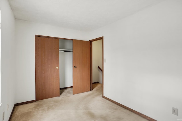 unfurnished bedroom with light carpet and a closet