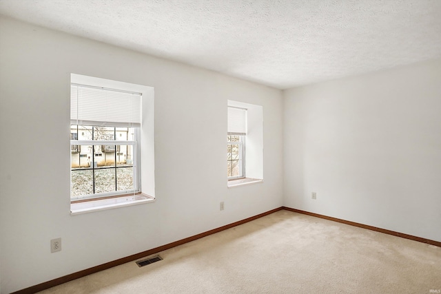 carpeted spare room with a textured ceiling