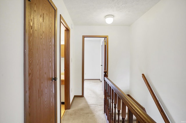 hall with a textured ceiling and light colored carpet