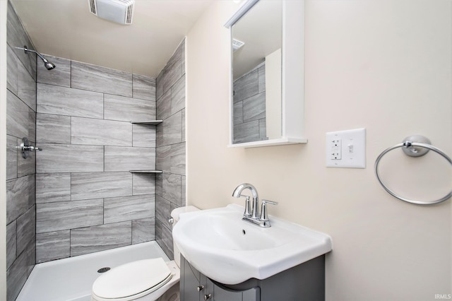 bathroom with tiled shower, vanity, and toilet