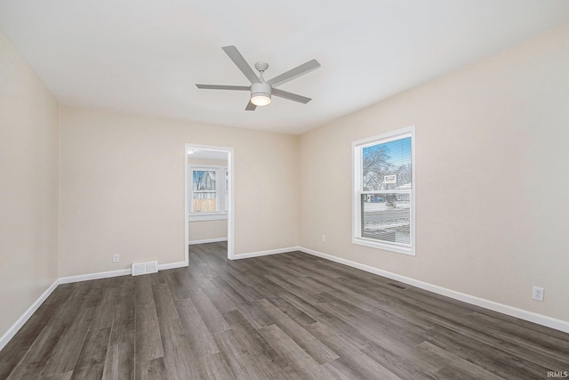 unfurnished room with ceiling fan, plenty of natural light, and dark wood-type flooring