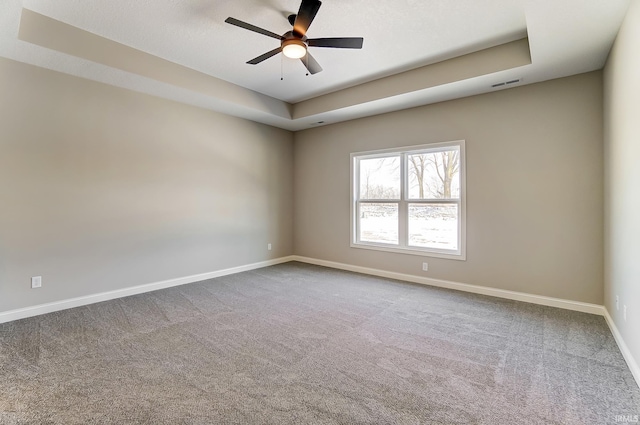 spare room featuring carpet flooring, ceiling fan, and a raised ceiling