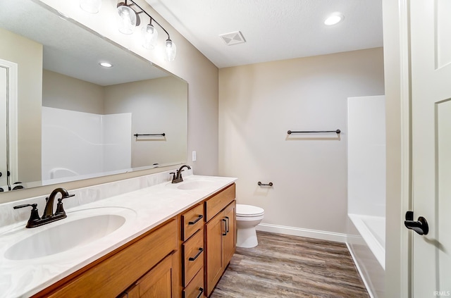 bathroom with wood-type flooring, vanity, a textured ceiling, and toilet