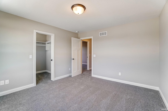 unfurnished bedroom featuring a walk in closet, carpet floors, and a closet