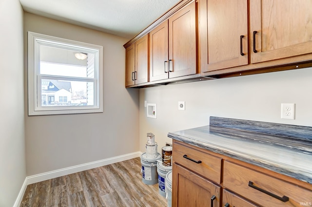 laundry room with electric dryer hookup, hookup for a washing machine, cabinets, and light hardwood / wood-style floors