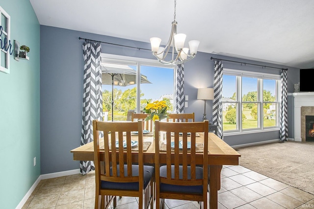 carpeted dining area featuring a chandelier and a tiled fireplace