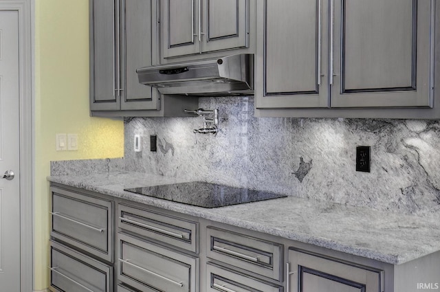 kitchen with tasteful backsplash, gray cabinets, and light stone counters