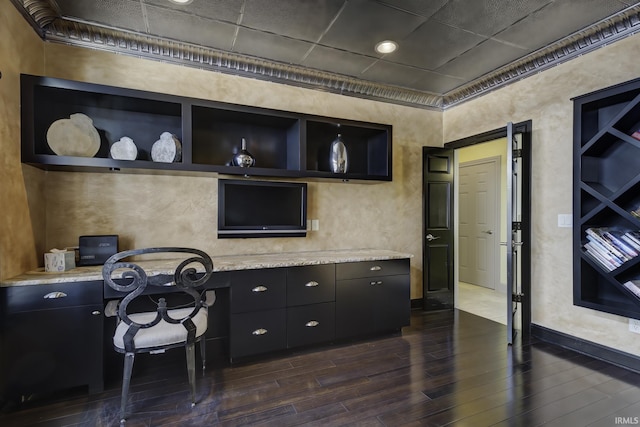 kitchen featuring built in shelves, light stone counters, dark wood-type flooring, and built in desk