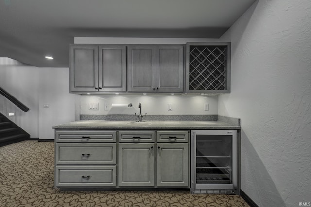 bar with beverage cooler, gray cabinetry, and sink