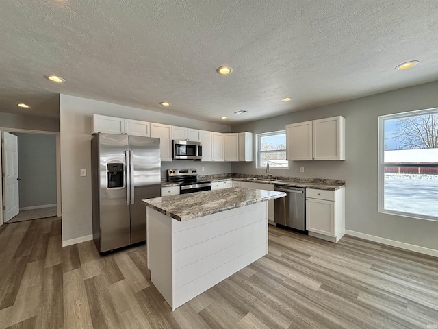 kitchen featuring white cabinets, a center island, light wood-type flooring, and appliances with stainless steel finishes