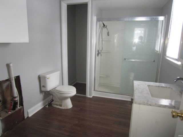 bathroom featuring hardwood / wood-style floors, vanity, toilet, and a shower with door