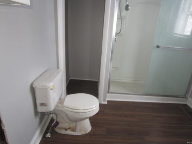 bathroom featuring wood-type flooring, an enclosed shower, and toilet