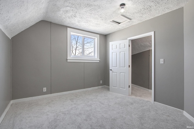 unfurnished bedroom featuring a textured ceiling, light carpet, and vaulted ceiling