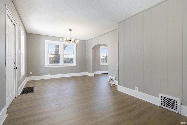 interior space featuring wooden walls, a chandelier, and dark hardwood / wood-style floors