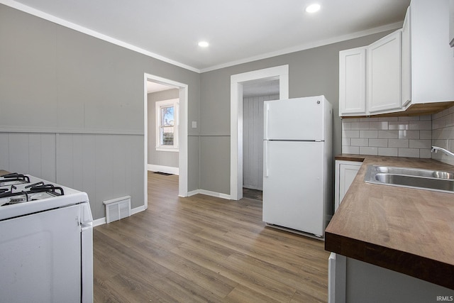 kitchen featuring white appliances, white cabinets, sink, light hardwood / wood-style flooring, and ornamental molding