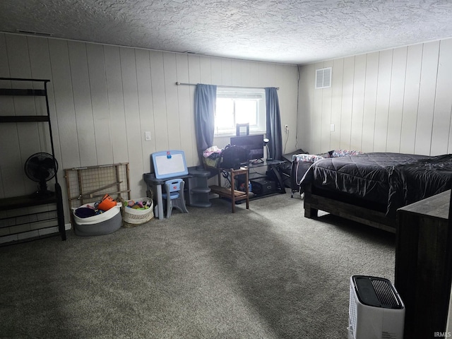 carpeted bedroom with a textured ceiling and wooden walls