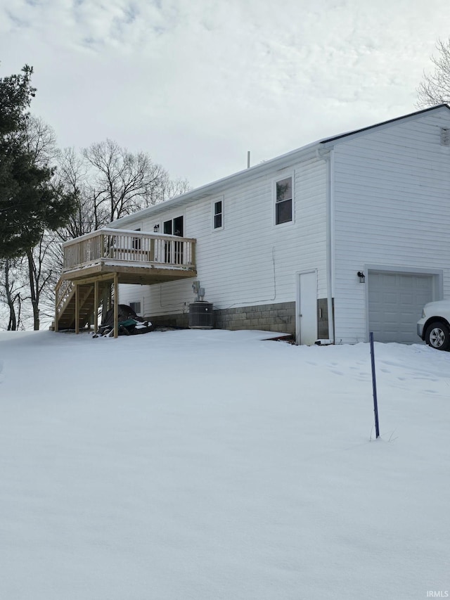 snow covered back of property featuring cooling unit and a wooden deck