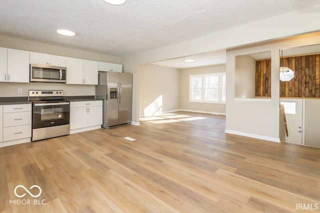 kitchen featuring pendant lighting, light hardwood / wood-style floors, white cabinetry, and stainless steel appliances