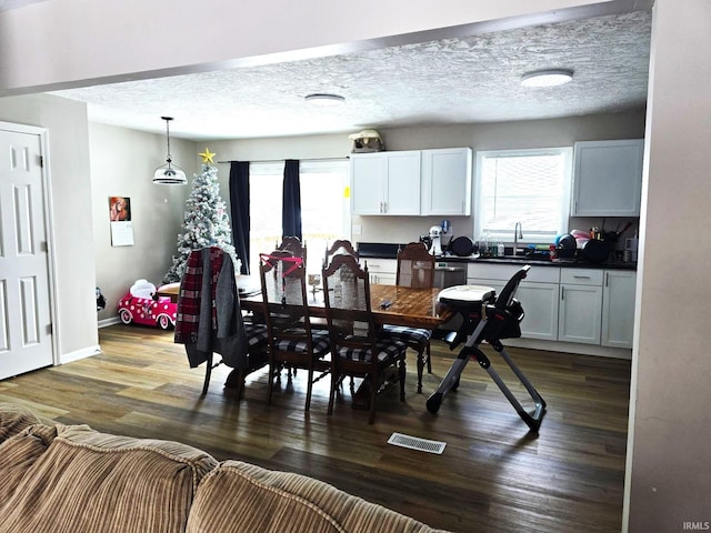 dining area with a textured ceiling, dark wood-type flooring, and sink