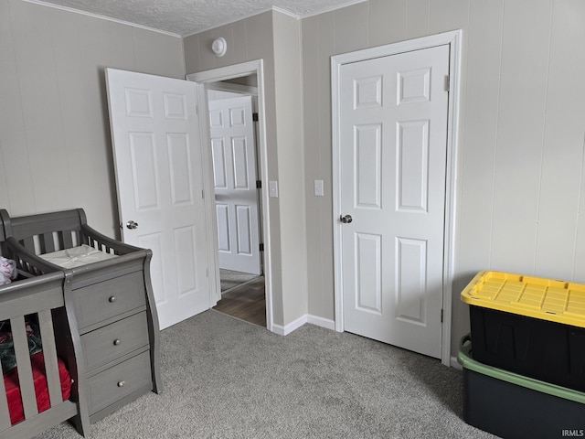 carpeted bedroom featuring a crib and a textured ceiling