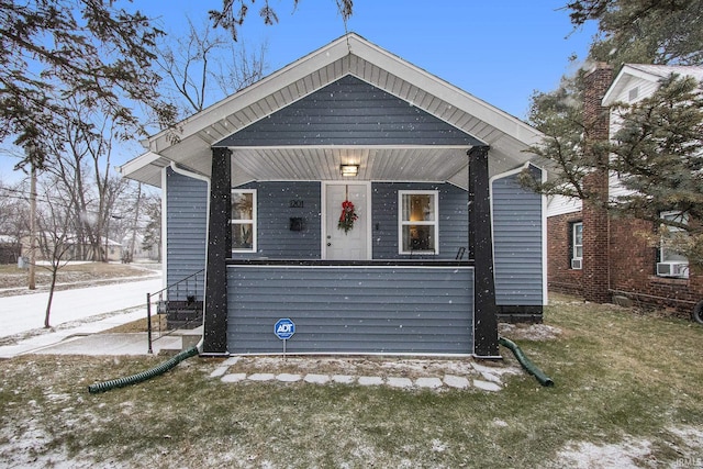 bungalow-style home featuring covered porch and a front lawn