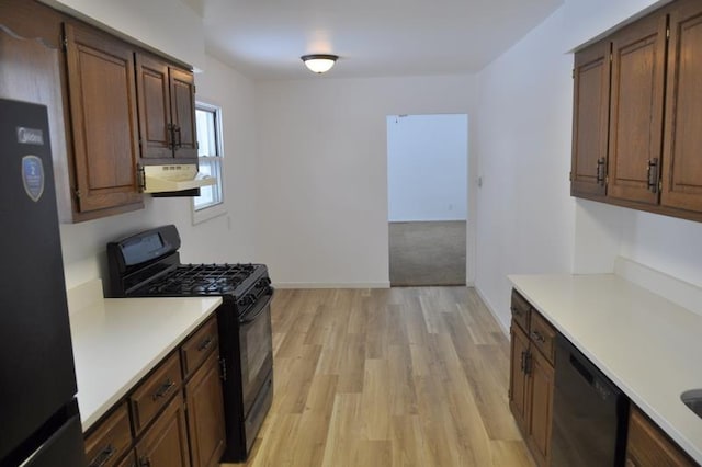 kitchen with black appliances, light wood-type flooring, and exhaust hood