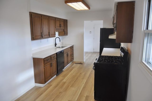 kitchen featuring black appliances, light wood-type flooring, and sink