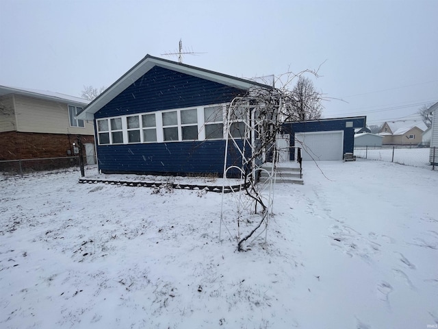 snow covered house with a garage and an outbuilding