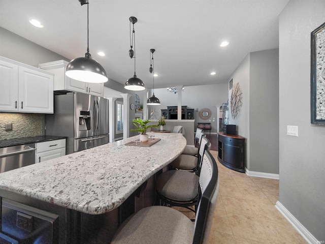 kitchen with a kitchen bar, appliances with stainless steel finishes, decorative backsplash, white cabinets, and hanging light fixtures