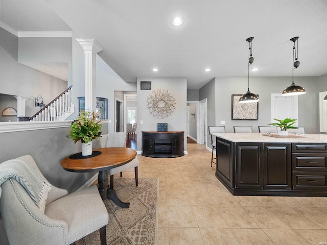 kitchen with hanging light fixtures, ornamental molding, light tile patterned floors, light stone counters, and decorative columns