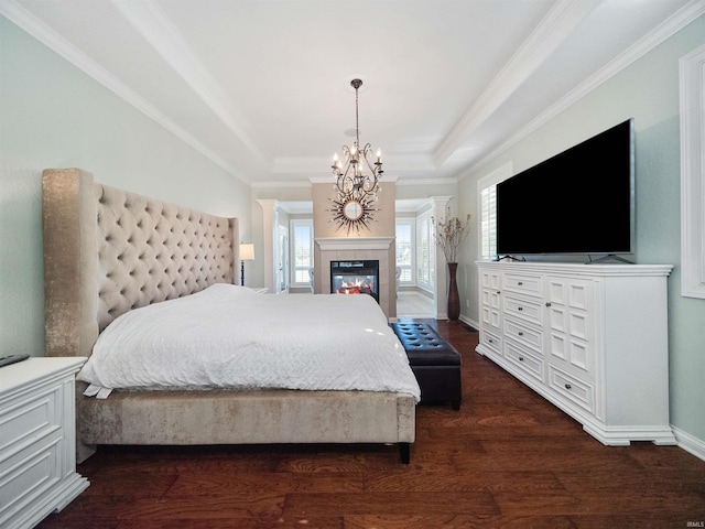 bedroom featuring a tile fireplace, dark wood-type flooring, a raised ceiling, crown molding, and a chandelier