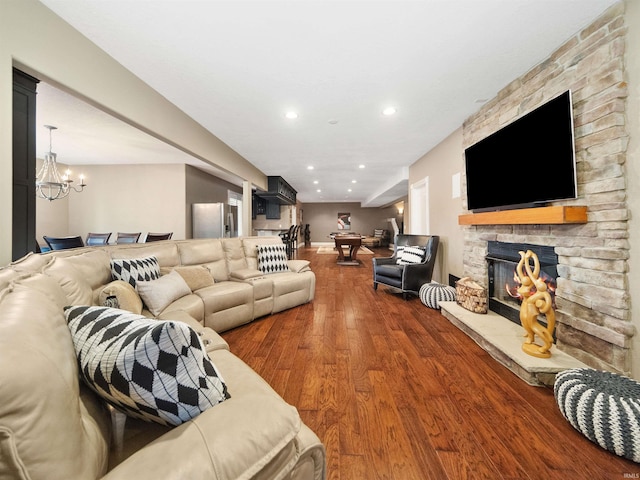 living room featuring a stone fireplace, hardwood / wood-style floors, and a chandelier