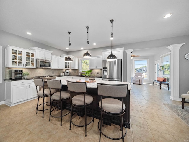 kitchen with ceiling fan, appliances with stainless steel finishes, decorative light fixtures, a kitchen island, and white cabinetry