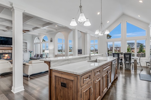 kitchen with ornate columns, sink, a center island with sink, a notable chandelier, and hanging light fixtures