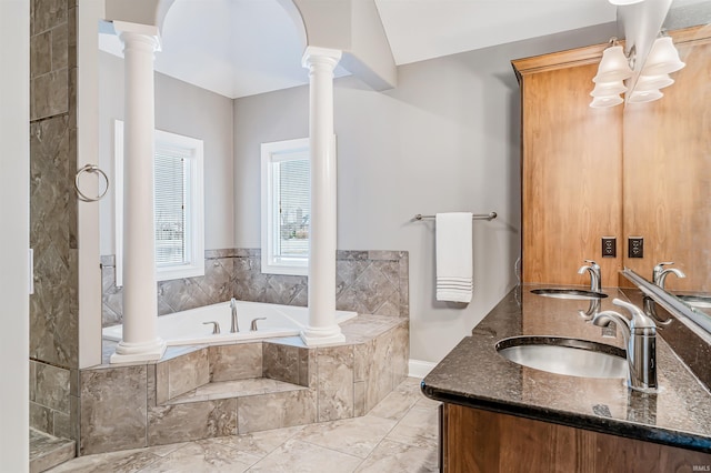 bathroom featuring vanity, decorative columns, and tiled tub