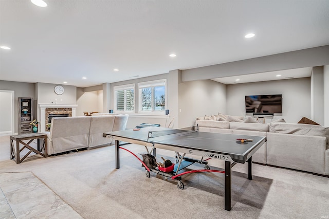 recreation room featuring a stone fireplace and light colored carpet