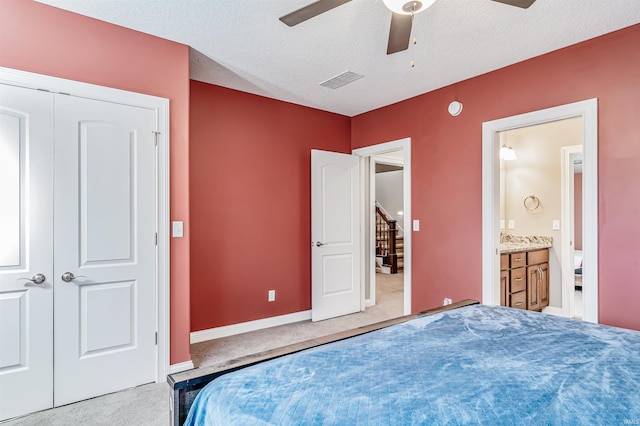 bedroom with ensuite bathroom, ceiling fan, a textured ceiling, light colored carpet, and a closet