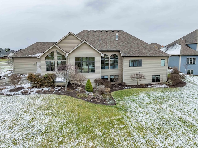 snow covered house featuring a lawn