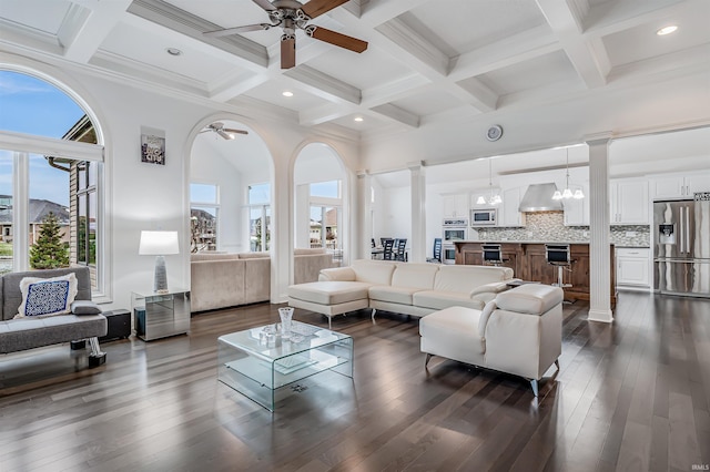 living room featuring dark wood-type flooring, beamed ceiling, a notable chandelier, decorative columns, and a towering ceiling