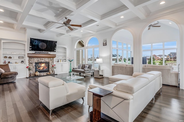 living room with built in shelves, a stone fireplace, and plenty of natural light