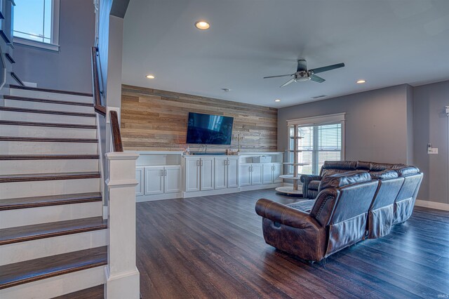 living room with ceiling fan, dark hardwood / wood-style flooring, and wooden walls