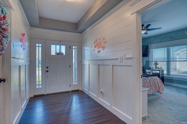 foyer entrance with ceiling fan and dark carpet