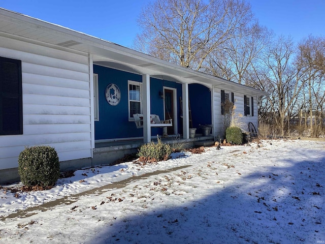 snow covered property entrance featuring a porch