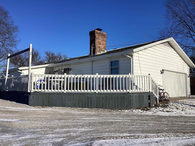 snow covered property featuring a garage and a deck