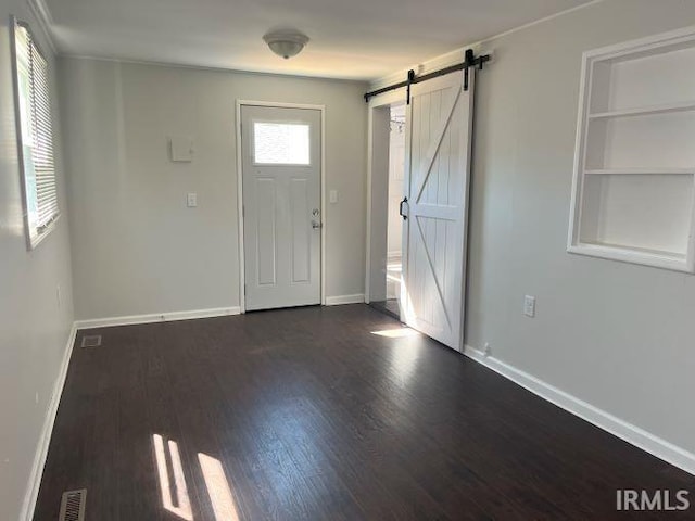 foyer with a barn door, a healthy amount of sunlight, and dark wood-type flooring