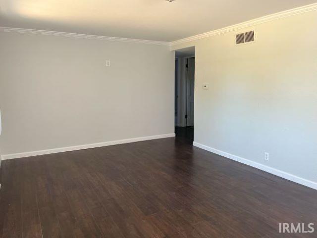 empty room with dark hardwood / wood-style floors and ornamental molding