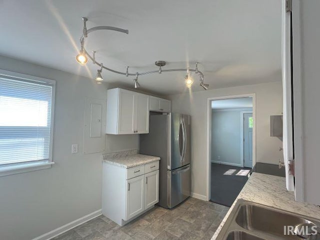 kitchen featuring stainless steel fridge, white cabinetry, and sink