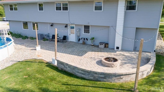 back of property featuring a lawn, a patio, and a fire pit