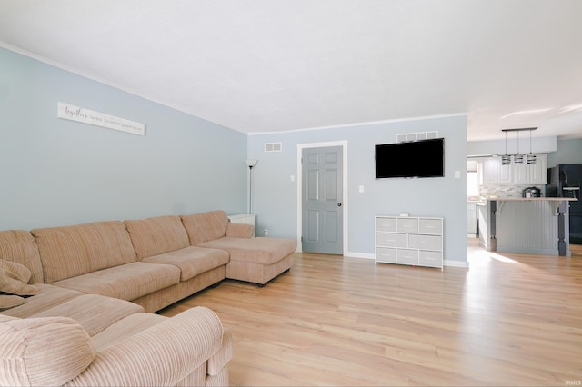 living room featuring crown molding and light hardwood / wood-style flooring